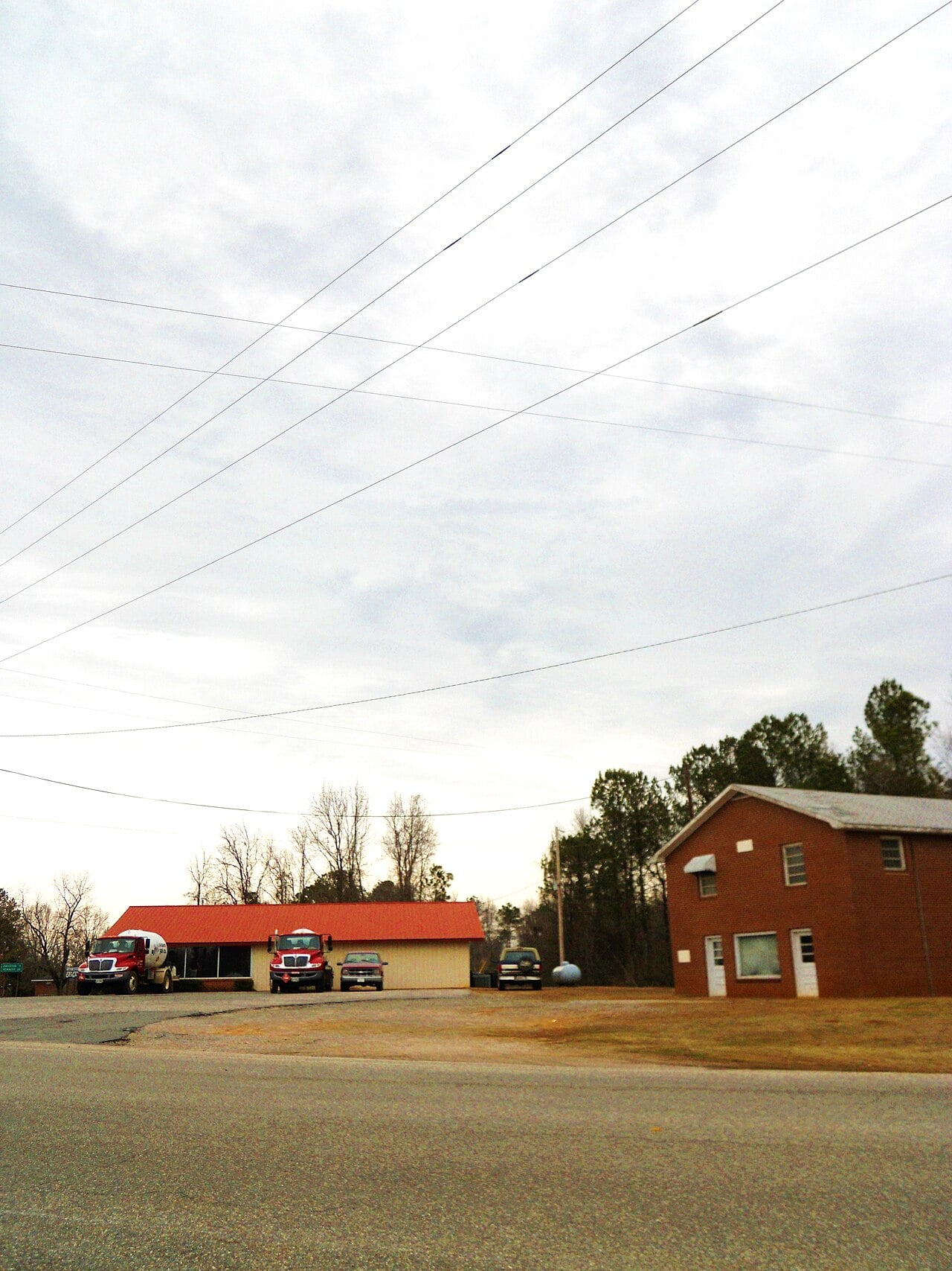 Fire station and community building with parked trucks and a brick building in a rural area.