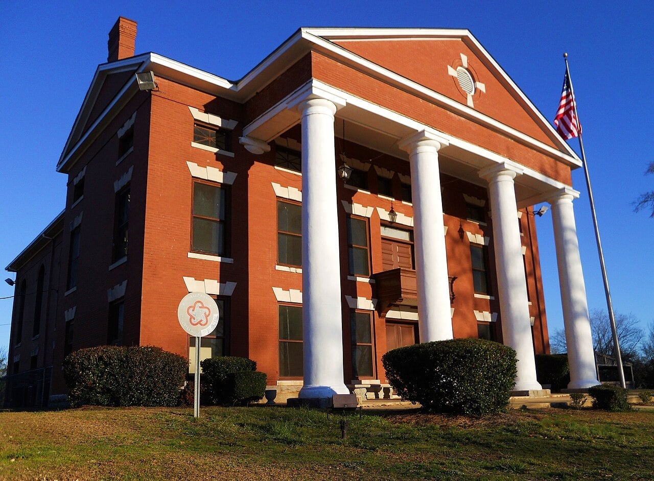 Courthouse with classic architecture, white columns, and American flag in the background.